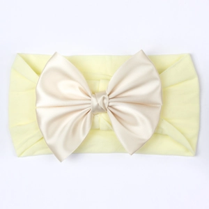 Détail d'un bandeau souple pour bébé orné d'un grand nœud en satin couleur champagne