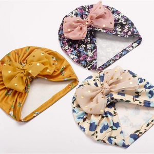 Vue détaillée de trois bonnets pour bébé avec imprimés floraux et nœuds en tulle à pois dorés