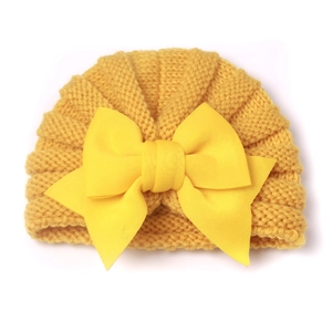 Détail d'un bonnet de bébé en tricot jaune avec un grand nœud décoratif pour l'hiver