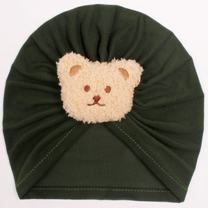 Detail of baby bear beanie in dark green with soft brown plush bear patch and pleated fabric