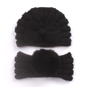 Close-up of baby warm knit beanie hat and headband set with faux fur pom pom in black