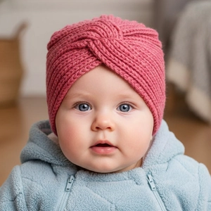 Dettaglio del cappello a turbante in maglia rosa per neonati con nodo a croce invernale