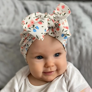 Close-up of baby headband with large bow and colorful floral prints on white ribbed fabric