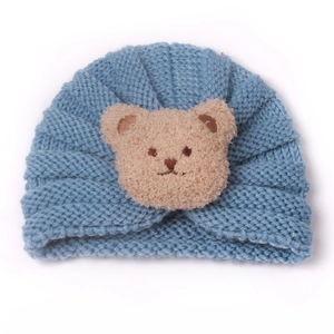Detailed close-up of light blue knit baby turban hat with a 3D plush bear patch decoration