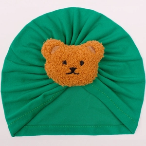 Detailed view of green cotton baby turban hat with a plush 3D brown bear decoration