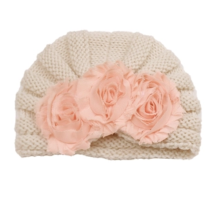Detailed knit texture and pink fabric flowers on a beige baby turban hat