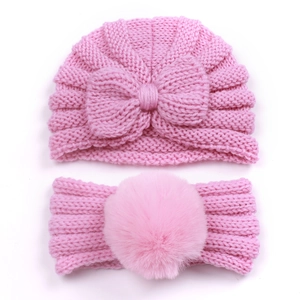 Detail of pink knitted baby beanie with bow and matching soft pom-pom headband