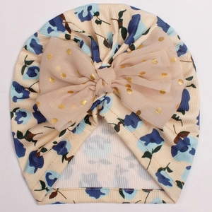 Détail du bonnet bébé côtelé à fleurs avec nœud en tulle à pois dorés de couleur beige