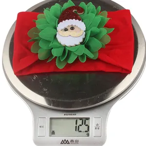 Detailed view of Christmas baby headband with Santa doll on an electronic scale weighing 12.5g