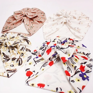 Detail of four floral baby beanies with large bows in soft ribbed cotton fabric