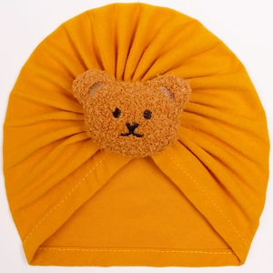 Detail of ginger yellow baby turban hat featuring a plush bear patch and knit texture