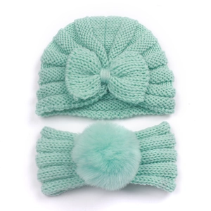 Detail of mint green baby knitted beanie and headband set with a large bow and soft pompom