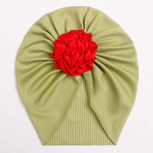 Detailed view of the ribbed knit fabric texture and large red satin flower on the baby hat