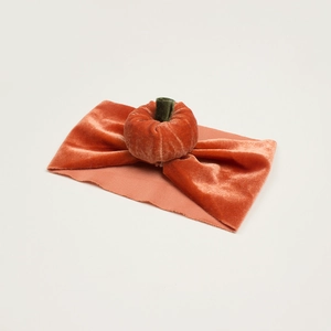 Detail of soft orange velvet baby headband with a plush stuffed pumpkin ornament
