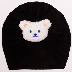 Close-up of black baby beanie with a white fleece bear patch and blue embroidery detail