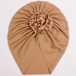 Detail of baby turban hat featuring pleated knit fabric and a large satin rose decoration