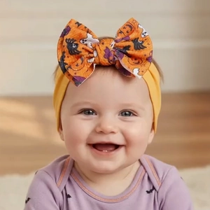 Detail of baby Halloween headband with pumpkin print orange waffle bow on yellow fabric
