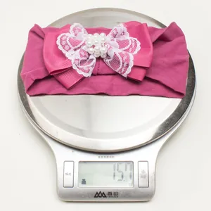 Gros plan d'un bandeau bébé en satin rose foncé léger avec nœud pesant 15,7 grammes