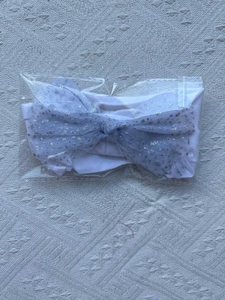 Detail of baby headband with grey sequined mesh bow in transparent plastic packaging