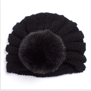 Détail du bonnet en tricot noir avec texture côtelée et pompon en fausse fourrure