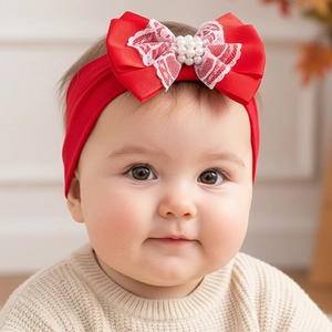 Détail d'un bandeau bébé à nœud en satin rouge avec dentelle fine et ornements de perles