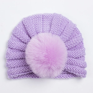 Détail d'un bonnet en tricot violet clair pour bébé avec pompon et texture côtelée