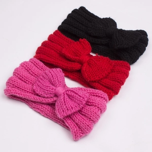 Close-up of cable knit bow headbands in pink, red, and black for baby girls