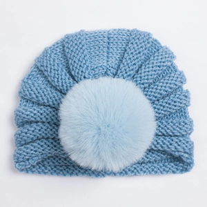 Détail de la maille côtelée et du pompon en fausse fourrure douce sur le bonnet de bébé