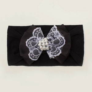Détail d'un bandeau pour bébé en nylon noir avec nœud en dentelle et perles