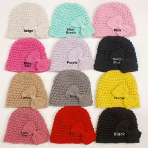 Flat lay of 12 colorful knit baby hats with bow accents in a 3x4 grid arrangement