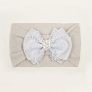 Vue détaillée du bandeau bébé blanc avec nœud en dentelle multicouche et perles nacrées