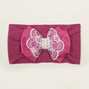 Détail du bandeau bébé rose avec dentelle et perles blanches sur le joli nœud
