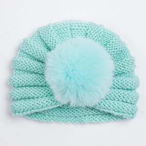 Détails du tricot de ce bonnet bébé vert menthe avec un gros pompon en fausse fourrure