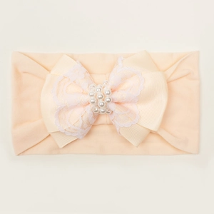 Détail du bandeau bébé abricot avec nœud floral en dentelle et perles blanches