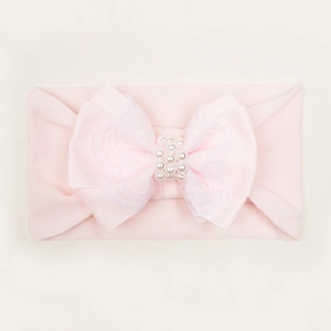 Détail d'un bandeau rose pour bébé avec nœud en dentelle et accents de perles blanches