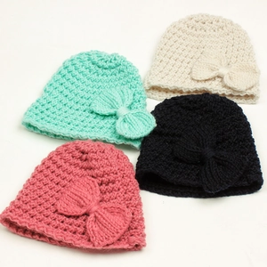 Detailed texture of knitted baby beanies with bows in mint, cream, pink and navy