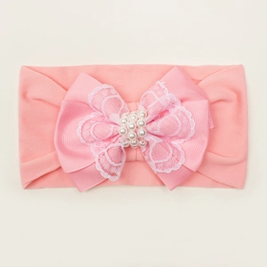 Détail du bandeau rose pour bébé avec nœud en dentelle et perles nacrées blanches