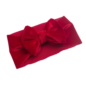 Detailed view of red velvet bow headband with textured elastic band for baby girls