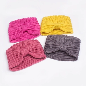 Set of four warm knitted baby hats with knotted bows in magenta, yellow, red and grey