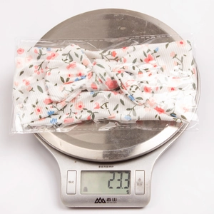 Close-up of lightweight floral bow headband weighing 23.3g on a digital scale