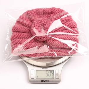 Pink knit baby turban hat weight display showing 50.4 grams on digital scale