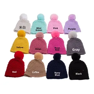 Flat lay of knit baby beanies in 12 colors featuring pom-poms and crochet texture