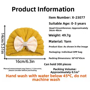 Détail d'un bonnet tricoté jaune pour bébé avec un grand nœud rose orné de perles