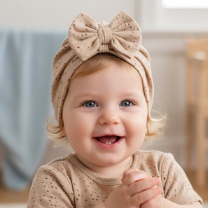 Close-up of baby turban hat with large bow and breathable mesh texture in beige