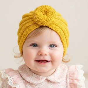 Close-up of mustard yellow baby turban hat showing soft knit ribbing and donut detail