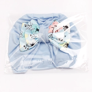 Detailed close-up of light blue baby turban hat with floral bow in packaging