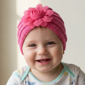 Détail d'un bonnet turban en tricot rose pour bébé orné d'une grande fleur de rose