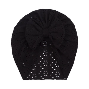 Detail of black infant turban hat with eyelet hollow design and large bow accent