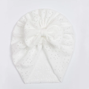 Detailed view of white eyelet hollow embroidery baby turban hat with large bow decoration