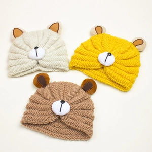 Detailed flat lay of soft knit baby beanies with cute bear ears in cream, yellow and brown
